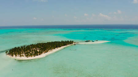 Tropical landscape: small island with beautiful beach, palm trees by turquoise water view from...