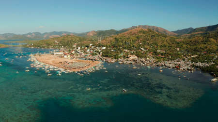 aerial view City Quay with boat dock and public market Coron town, tourist destination in the Philippines. Pier and promenade with boats on Busuanga island. Wooden boats waiting at pier. Seascape with mountains.の写真素材