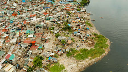 Slums in Manila on the bank of a river polluted with garbage, aerial view.の写真素材