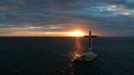 Catholic cross in sunken cemetery in the sea at sunset, aerial drone. colorful sky during the sunset. Large crucafix marking the underwater sunken cemetary, Camiguin Island Philippines.の写真素材