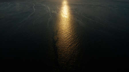 Sunset above the sea surface with waves, aerial drone. Reflected sun on a water surface. Sunset over...