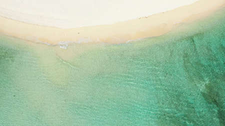 Soft blue sea wave on a clean sandy beach, top view. Transparent lagoon and white sand. Summer and...