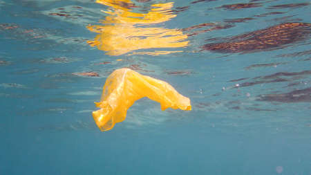 Plastic bag floating in clear water in the sea. Ecological problem.の写真素材
