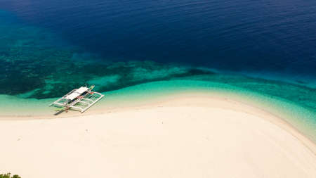 Tropical beach of white sand, top view. Tourist boat off the coast. Blue sea with turquoise lagoons. Summer and travel vacation concept. Tranquil beach scene.の写真素材