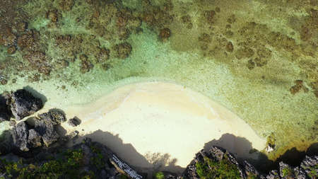 Travel concept: Sandy beach and turquoise water. Tourists on a tropical beach, aerial view. Marcos...