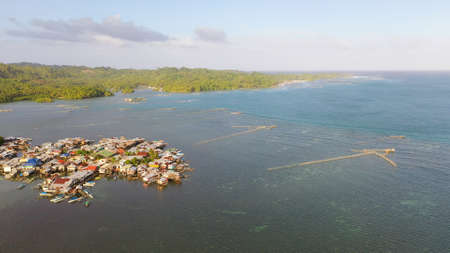 Traditional fishing village in Asia with fishing boats and houses standing in the sea. Philippines,...