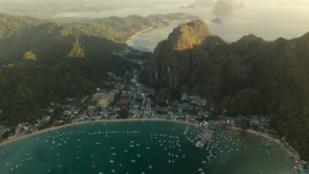 Aerial drone town on the coast with bay and lot tourist boats at sunrise, El nido, Palawan, Philippines. Seascape with blue bay and boats view from above. Summer and travel vacation conceptの写真素材