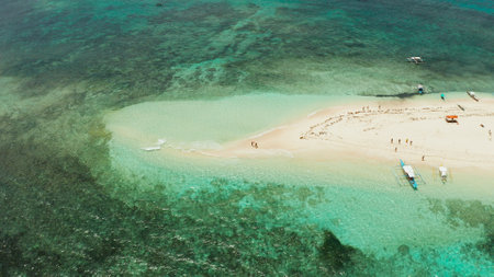 Beautiful beach on tropical island surrounded by coral reef, sandy bar with tourists, top view. Naked Island, Siargao.の写真素材