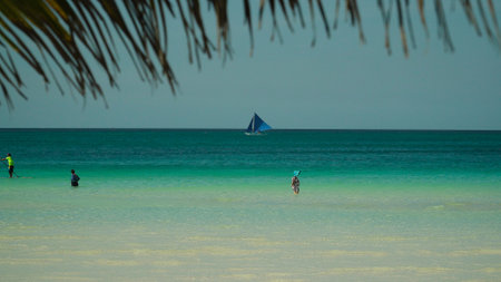 Tourists on a sandy beach and blue sea through palm branches. Summer and travel vacation concept....