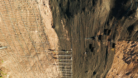 Workers strengthen the slope of the mountain with metal mesh preventing rockfall and landslide on the road, above view. workers constructing anti-landslide concrete wall prevent protect against rock slides. safety conceptの写真素材