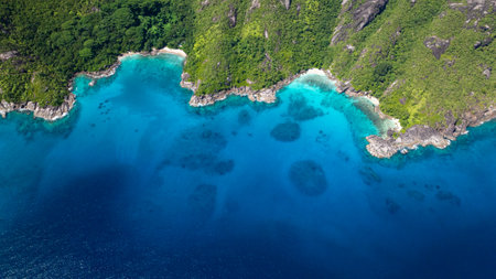 Green forested hills surround a turquoise bay with small beaches and rocky outcrops. Seychelles, Mahe.の写真素材