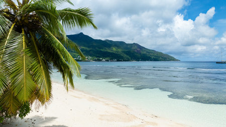 A sandy beach bordered by turquoise waters and lush green hills. Seychelles, Mahe. Beau Vallon Beach.の写真素材