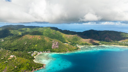 Lush green hills meet white sandy beaches and clear turquoise waters. Curieuse, Seychelles.の写真素材