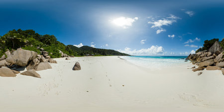 A peaceful beach featuring soft white sand, large granite boulders, and vibrant greenery under a bright sky. Petite Anse Beach, La Digue, Seychelles. Virtual Reality 360.の写真素材