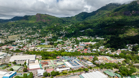A residential neighborhood surrounded by lush green hills with scattered houses and buildings. Victoria. Seychelles, Mahe.の写真素材