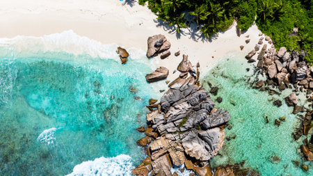 Crystal clear water meeting a rocky shore on a serene tropical beach. Anse Cocos beach. La Digue, Seychelles.の写真素材