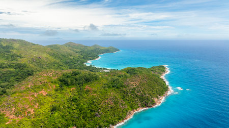 Aerial view of green hills leading to quiet turquoise bays with white sandy beaches, tucked along a peaceful coastline. Praslin, Seychelles.の写真素材