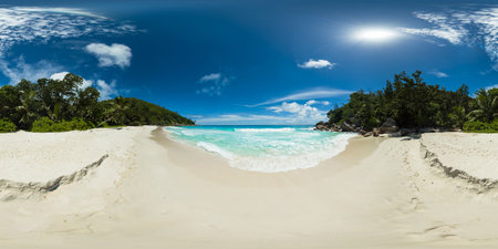 A tropical beach with turquoise waters, white sand and lush greenery under a clear blue sky. Anse...