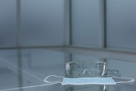 Safety goggles and protective medical mask on glass tableの写真素材