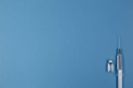 Medical Syringe and vaccine on blue background
