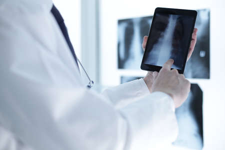 healthcare, clinic and medical concept - group of doctors looking at x-ray on tablet pcの写真素材