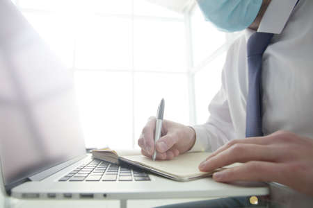 Businessman working in the office he protects himself from the virus  by use the face maskの写真素材