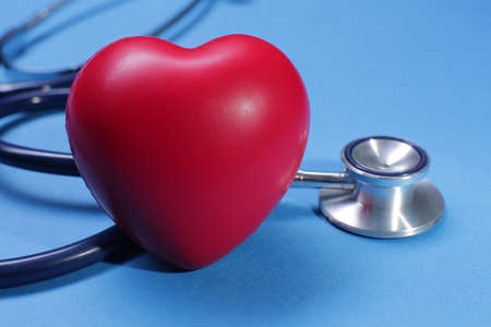 Red heart shape and medical stethoscope on blue background