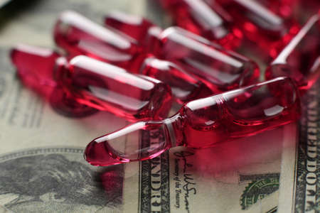 Glass vials with vaccine red and dollars. Close-upの写真素材