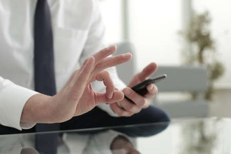 The company manager in office symbolizes success with one hand and holds the phone with the otherの写真素材