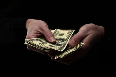 There is a large number of hundred dollar bills in human hands on black background