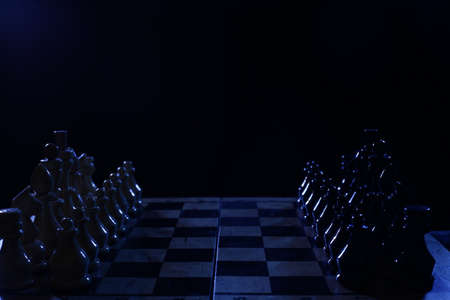 Wooden chess pieces on the board in darknessの写真素材