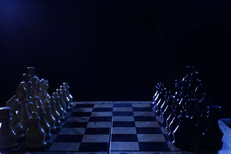 Wooden chess pieces on the board in darknessの写真素材
