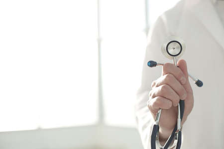 Doctor holding a stethoscope in a clinic roomの写真素材