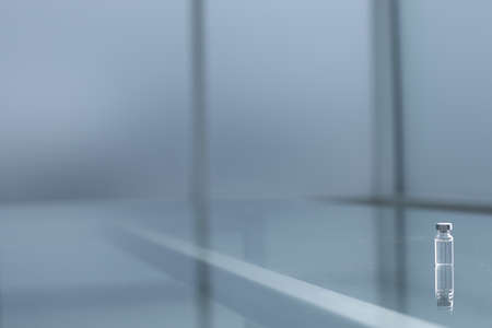 Medical vaccine in a glass bottle on a glass tableの写真素材
