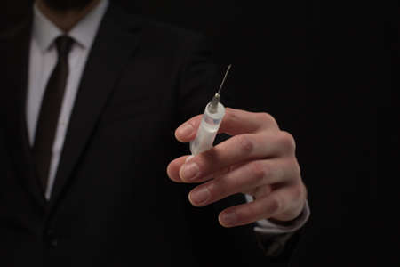 Human hand holding medical syringe with vaccine on black backgroundの写真素材