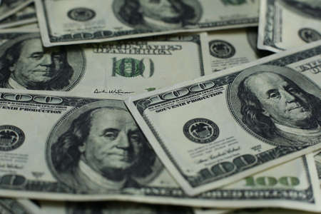 Lots of hundred US dollar bills on wooden table
