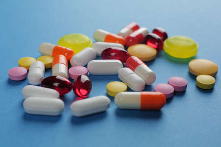 Multicolored pills of various shapes on a blue background. Close-upの写真素材