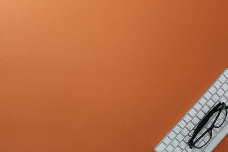 Glasses and keyboard on orange backgroundの写真素材