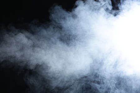 Illuminated smoke on black background in darkness