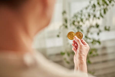 Old woman holds bitcoin coins in her hand. Senior citizen happy life concept