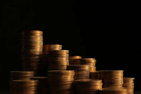 A large variety of coins on a black background. Stack of coinsの写真素材