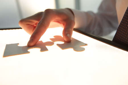 Businessmen assembling jigsaw puzzle and represent team support and help concept in office