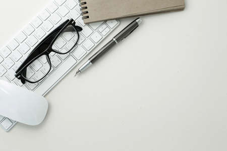 Glasses pen mouse keyboard and notepad on white background