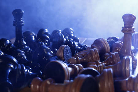 Chess is a board game. Chess wood pieces on a dark background in smokeの写真素材
