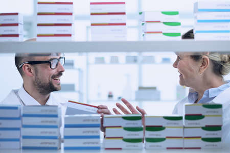 Pharmacists is working. Man and woman wearing medical uniform. People look through the patches in pharmacy.の写真素材