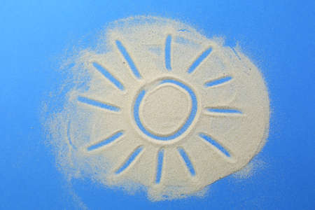 The symbol of the sun is written in the sand on a blue background