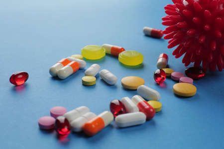 Multicolored pills of various shapes and imitation of  cell on a blue background