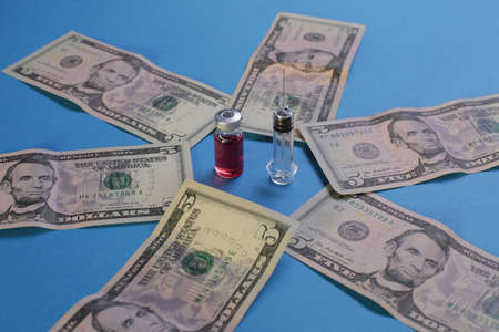 Syringe vial with vaccine and american dollars on blue background