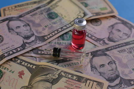 Syringe vial with vaccine on the background of American dollarsの写真素材