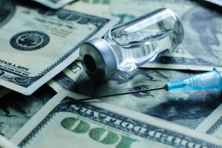 Vaccine vial and syringe on the background of one hundred dollar billsの写真素材